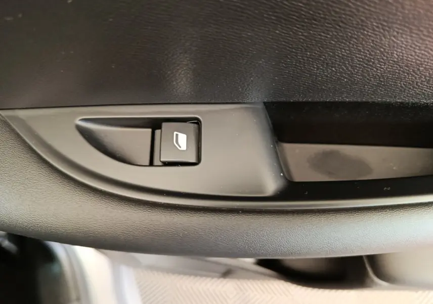 Détail du bouton de commande de lève-vitre sur la porte intérieure noire d'une DS3 2024 gris foncé.