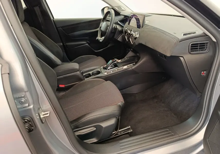 Vue intérieure côté passager d'une DS3 2024 gris foncé, avec tableau de bord moderne et sièges tissu noir.