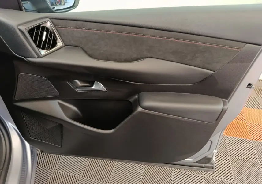 Vue rapprochée de la porte intérieure côté gauche gris foncé du DS3 2024 avec garniture en tissu et accoudoir intégré.