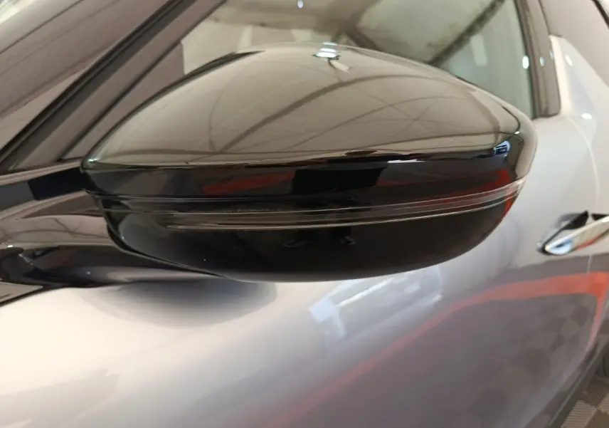 Gros plan sur le rétroviseur noir brillant côté gauche d'une DS3 gris foncé, avec reflet de l'environnement intérieur.