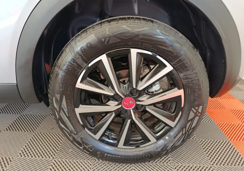 Gros plan sur la roue avant droite avec jante alliage noir et argent et logo DS rouge sur un DS3 gris foncé.
