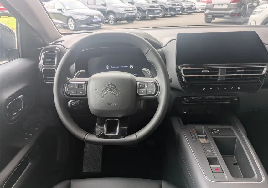 Vue intérieure centrée sur le volant cuir et la console centrale du Citroën C5 Aircross hybride 2025 gris platinium.