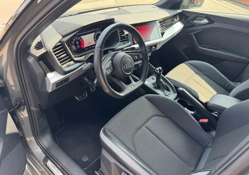 Intérieur gris de l'Audi A1 Sportback 2019 vu côté conducteur, avec tableau de bord numérique et volant sport.