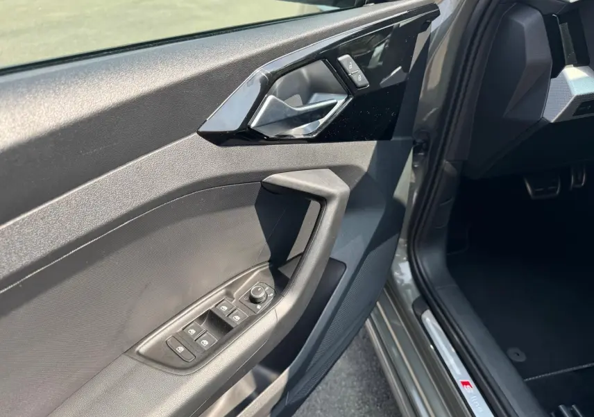 Gros plan sur la porte côté conducteur grise d'une Audi A1 Sportback 2019 avec commandes de vitres et badge S line.