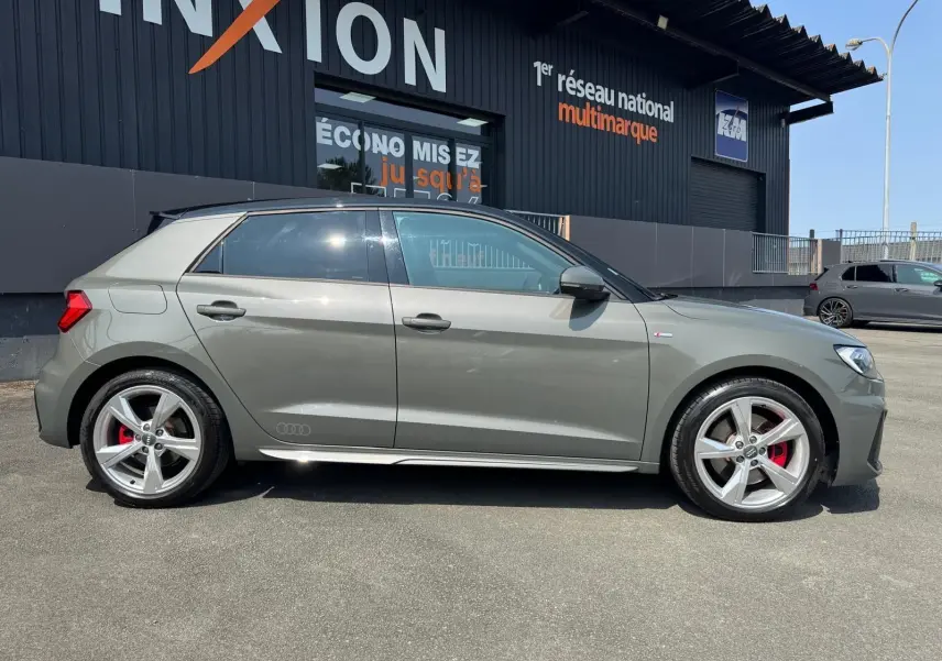 Audi A1 Sportback gris vue de profil côté gauche, avec jantes alliage et étriers de frein rouges visibles.
