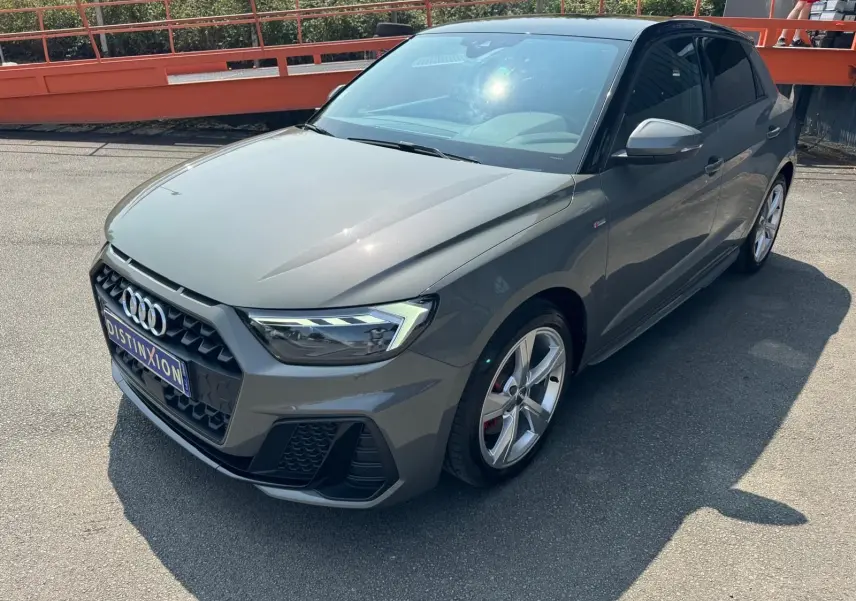 Audi A1 Sportback gris vue 3/4 avant droit, avec calandre hexagonale et jantes alliage cinq branches.