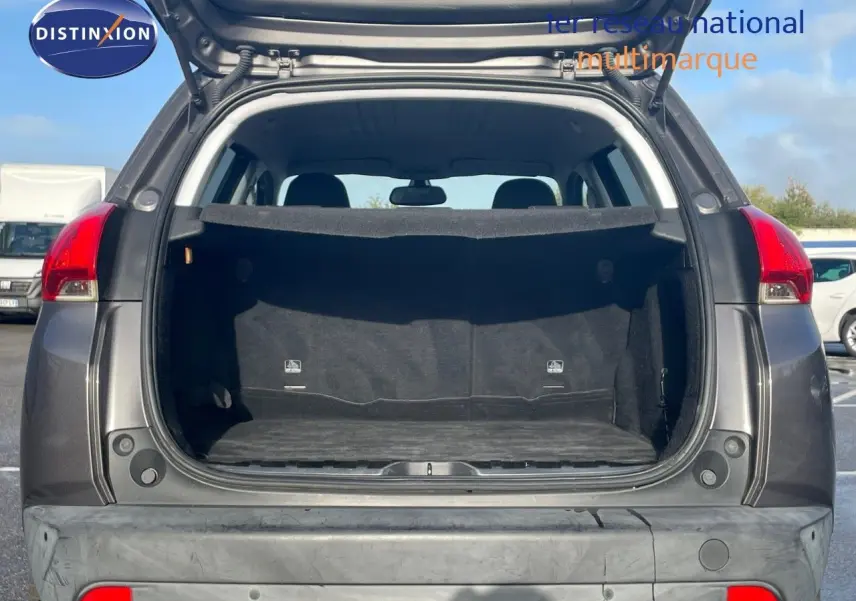 Vue arrière ouverte du coffre d'un Peugeot 2008 gris platinium métal, montrant l'espace de chargement vide.