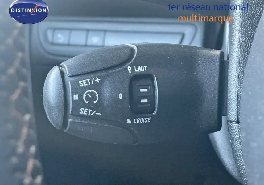 Gros plan sur la commande de régulateur de vitesse à gauche du volant dans un Peugeot 2008 gris platinium de 2019.
