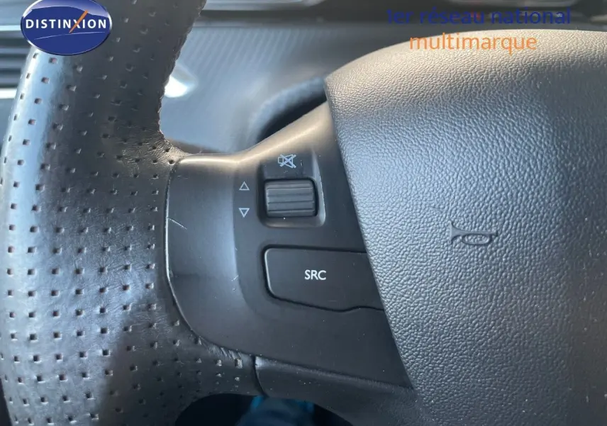Gros plan sur les commandes gauche du volant en cuir perforé noir du Peugeot 2008 gris platinium 2019.