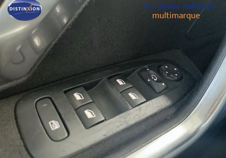 Gros plan sur les commandes des vitres électriques côté gauche d’une Peugeot 2008 gris platinium de 2019.