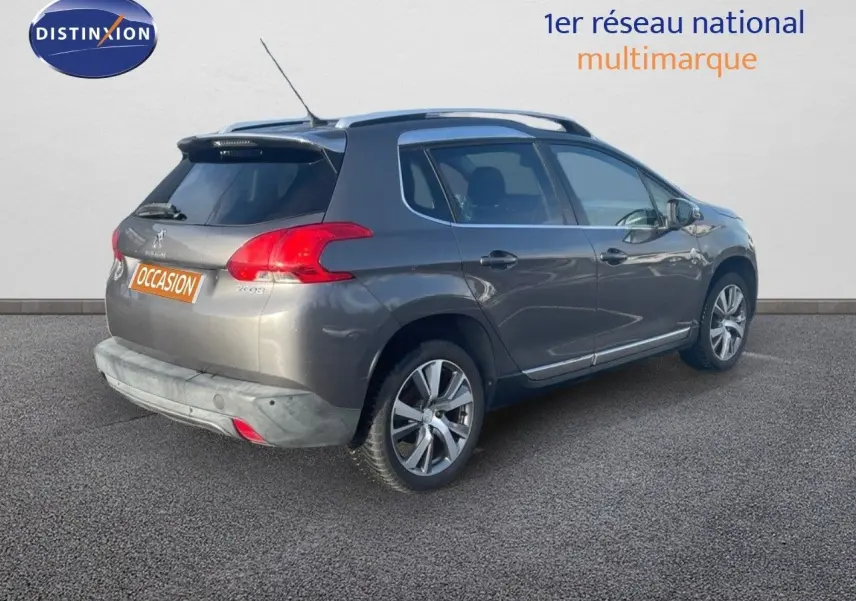 Peugeot 2008 gris platinium métal en 3/4 arrière droit, avec jantes alliage et barres de toit visibles.