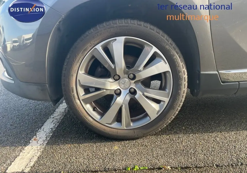 Gros plan sur la roue avant gauche d’un Peugeot 2008 gris platinium métal, mettant en valeur la jante alliage 17 pouces.