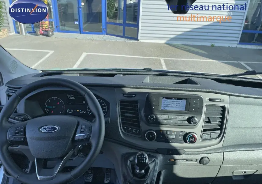 Vue intérieure du tableau de bord du Ford Transit Fourgon blanc 2023, avec volant multifonction et boîte manuelle.