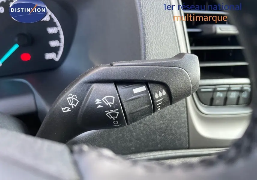 Gros plan sur la commande d’essuie-glace à gauche du volant dans l’habitacle d’un Ford Transit Fourgon blanc 2023.