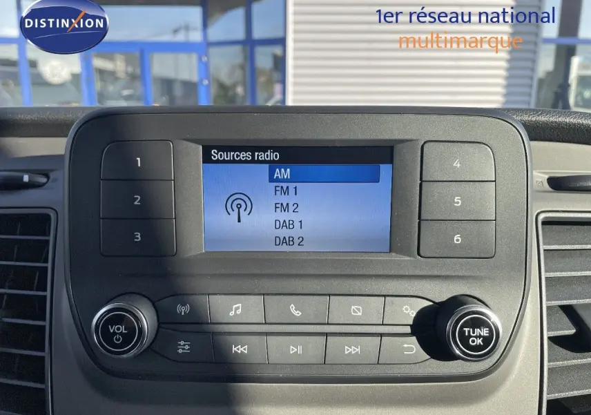Gros plan sur l'écran radio et les commandes du tableau de bord du Ford Transit Fourgon blanc 2023.