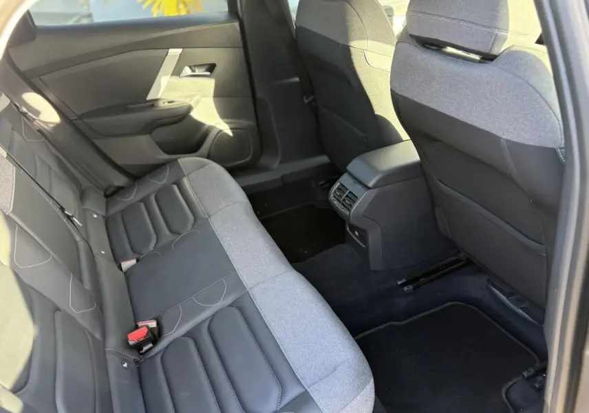 Vue intérieure arrière côté droit de la Citroën C4 2024, sièges bicolores gris et noir avec accoudoir central.