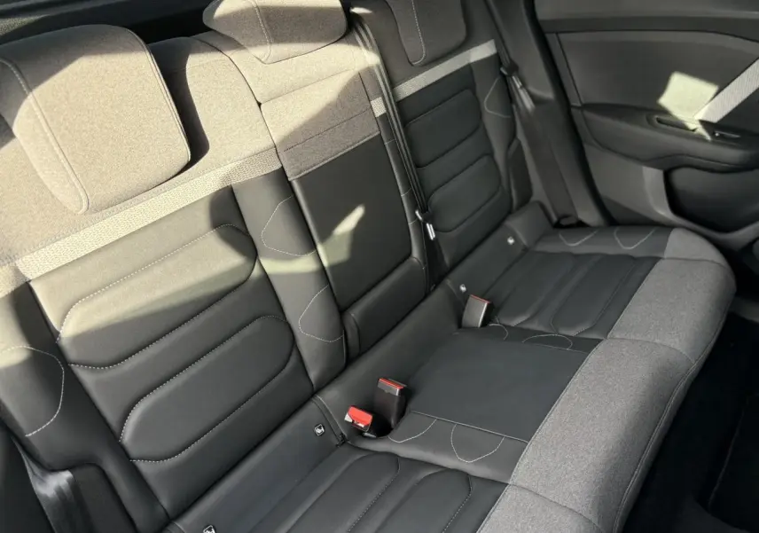 Vue intérieure du siège arrière droit de la Citroën C4 2024 avec sellerie bicolore gris et noir, détails couture visibles.