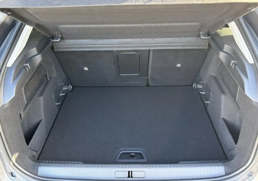 Coffre ouvert vu de l'arrière d'une Citroën C4 2024 gris Platinium, espace de chargement propre et modulable.