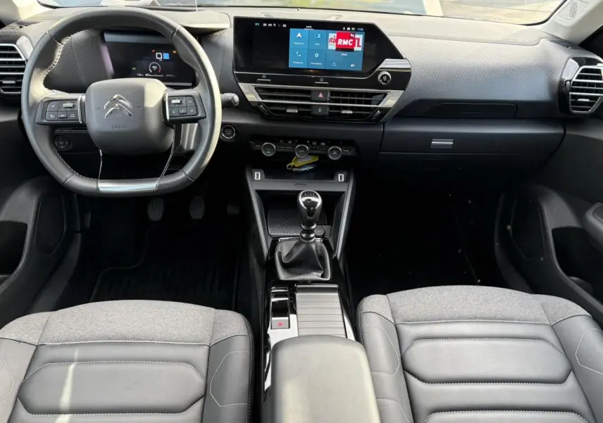 Vue intérieure avant du Citroën C4 2024, montrant tableau de bord, volant cuir, écran tactile 10 pouces et boîte manuelle.