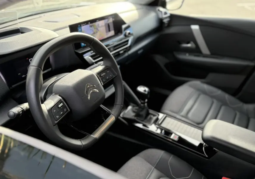 Vue intérieure côté conducteur de la Citroën C4 2024 gris Platinium, avec volant multifonction et écran tactile GPS 10 pouces.