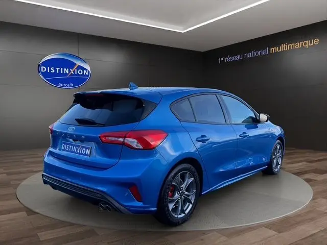 Vue 3/4 arrière droite d'une Ford Focus 1.5 EcoBoost 150ch ST-Line BVA bleu 2022, avec jantes sport et double sortie d'échappement.
