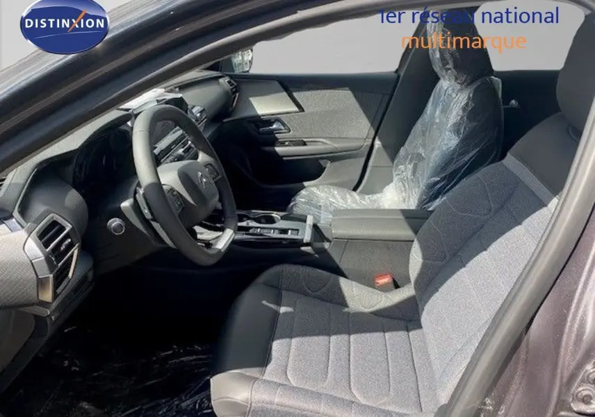 Vue intérieure côté conducteur du Citroën C5 X 2023, sièges tissu gris et cuir noir, volant multifonction et tableau de bord moderne.