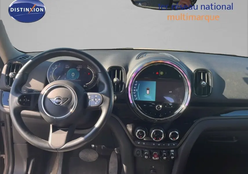 Vue intérieure avant du tableau de bord et volant d'une MINI Countryman Cooper 2023 avec écran central rond et finitions noires.