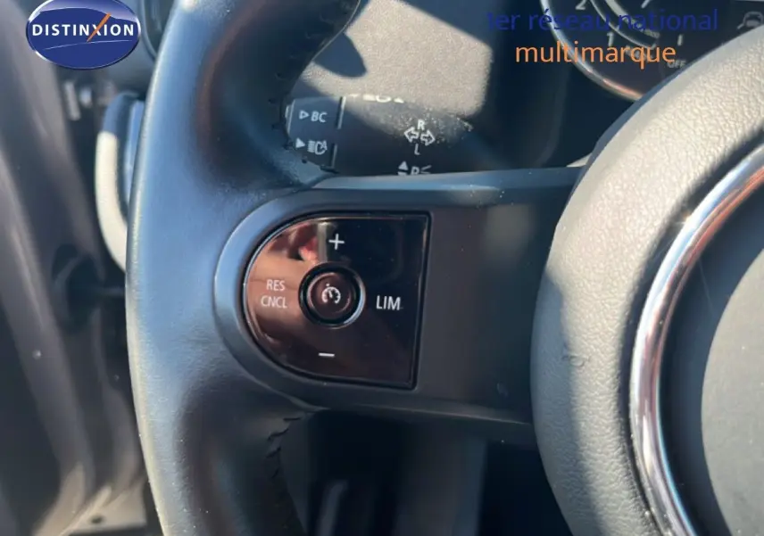 Gros plan sur les commandes de régulateur de vitesse au volant cuir noir d'une MINI Countryman 2023 Rooftop Grey.