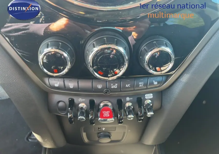 Vue rapprochée de la console centrale du MINI Countryman 2023, mettant en valeur les commandes de climatisation et le bouton start/stop rouge.