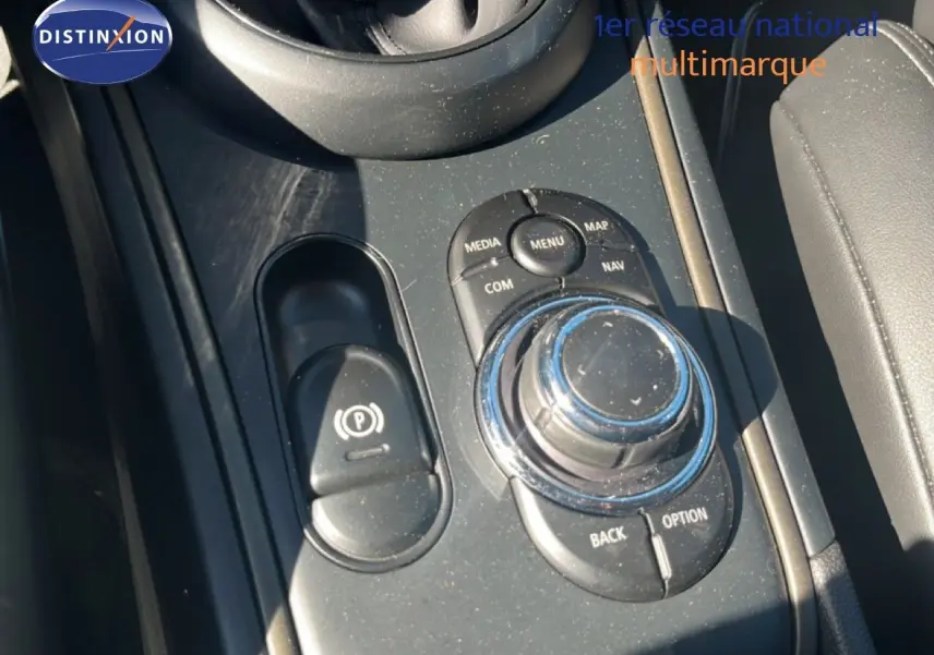 Gros plan sur la console centrale noire du MINI Countryman Cooper 2023, avec molette de commande et frein à main électrique.