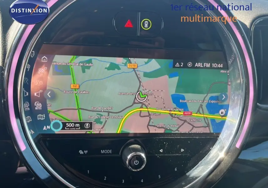 Vue rapprochée de l’écran central rond du MINI Countryman gris, affichant la navigation GPS avec éclairage LED violet.