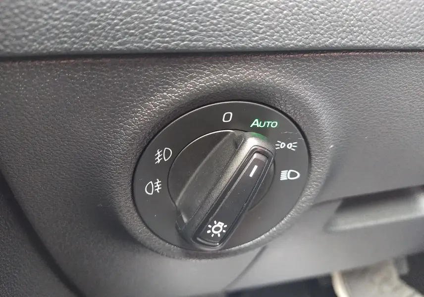 Gros plan sur le bouton de commande des phares du Skoda Karoq gris, avec mode automatique activé.
