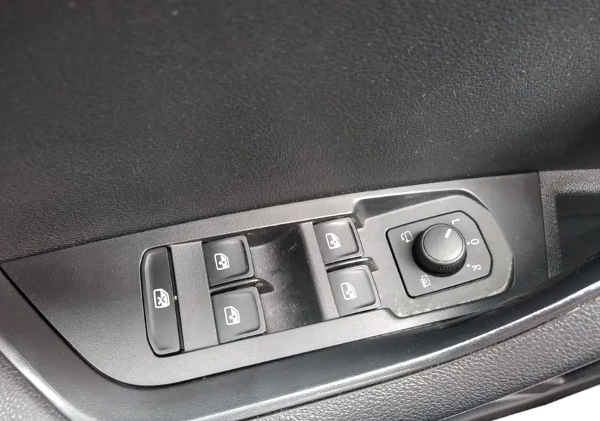 Gros plan sur les commandes des vitres et des rétroviseurs côté conducteur d'un Skoda Karoq gris 2021.