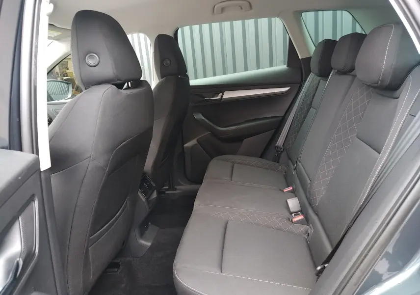Vue intérieure côté droit des sièges arrière noirs en tissu du Skoda Karoq gris, avec détails de couture apparents.