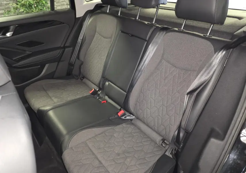 Vue intérieure arrière du Volkswagen Tiguan 2025 noir, montrant la banquette en tissu gris avec motifs géométriques.