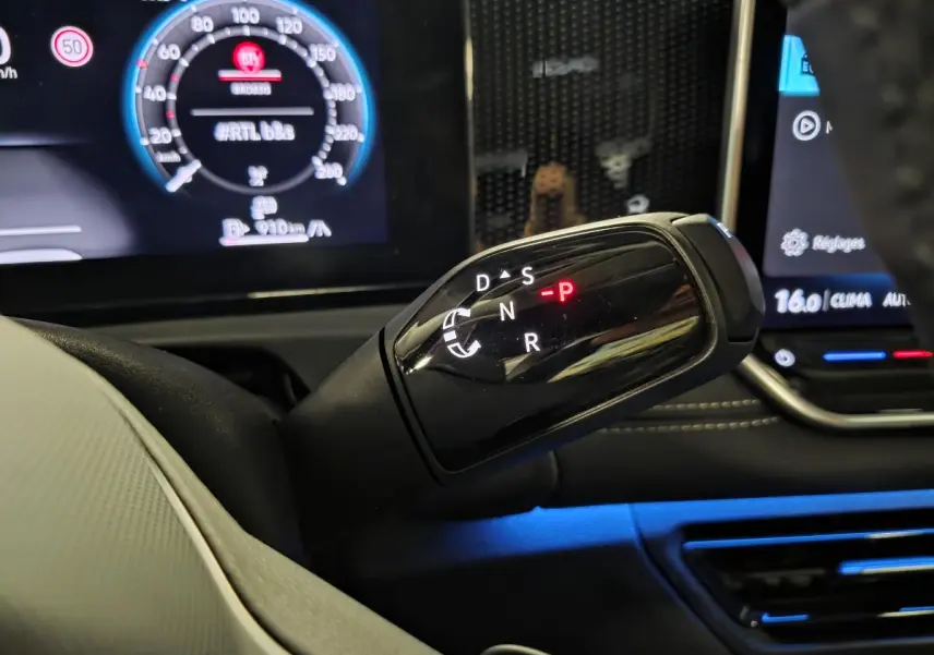 Gros plan sur le levier de vitesses noir brillant d’une Volkswagen Tiguan 2025, avec tableau de bord numérique en arrière-plan.