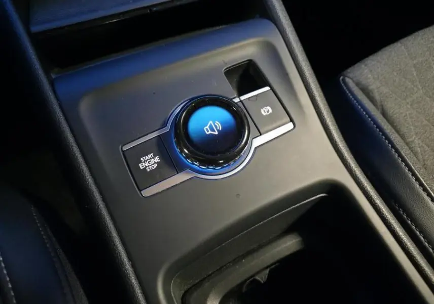 Gros plan sur la console centrale noire du Volkswagen Tiguan 2025, avec bouton start/stop et frein à main électronique.