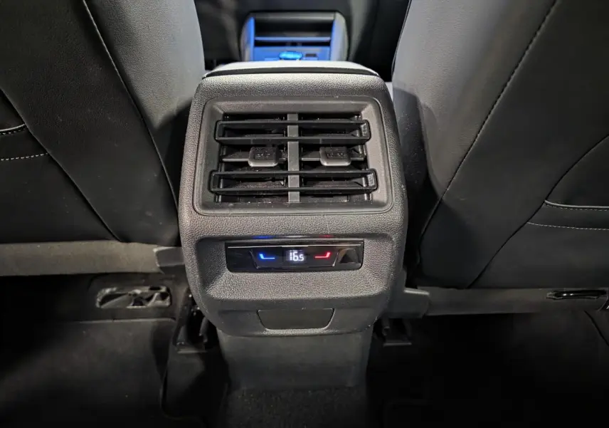 Vue rapprochée de la console centrale arrière noire du Volkswagen Tiguan 2025 avec ventilation et réglage climatique digital.