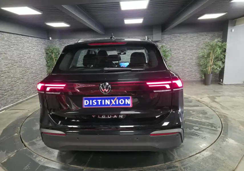 Vue arrière d'un Volkswagen Tiguan noir 2025 avec feux arrière LED allumés dans un showroom.