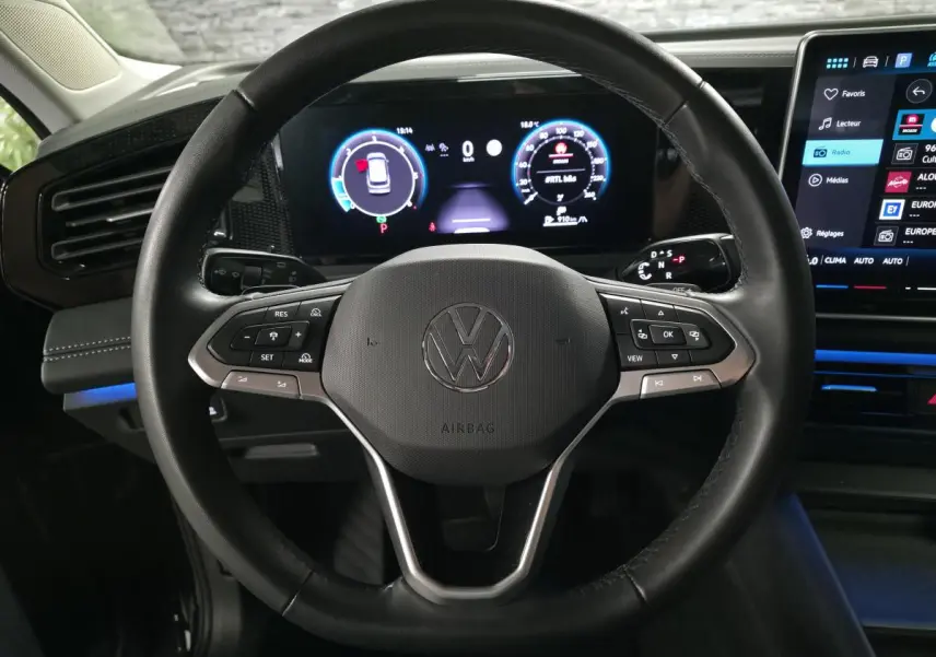 Vue rapprochée du volant en cuir noir du Volkswagen Tiguan 2025 avec tableau de bord numérique et écran tactile central.