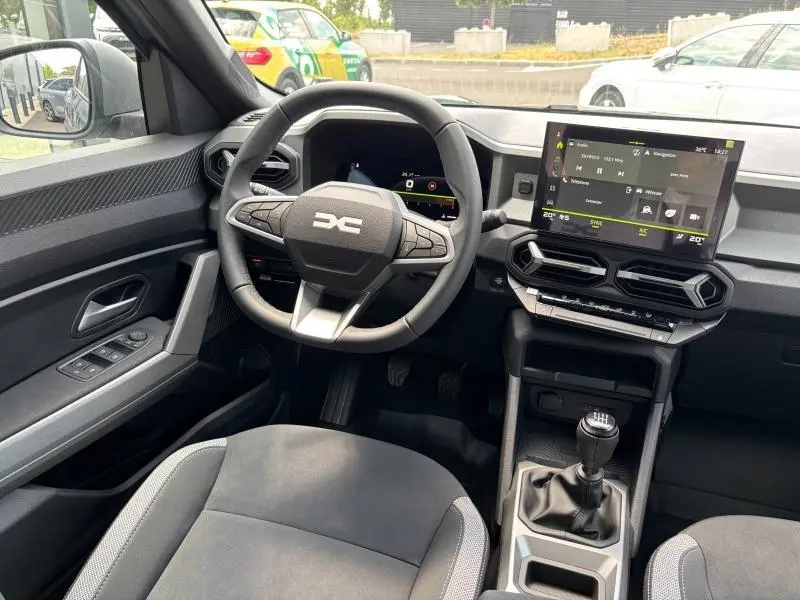 Vue intérieure avant du Dacia Bigster 2025, tableau de bord moderne avec écran tactile et volant multifonction noir.