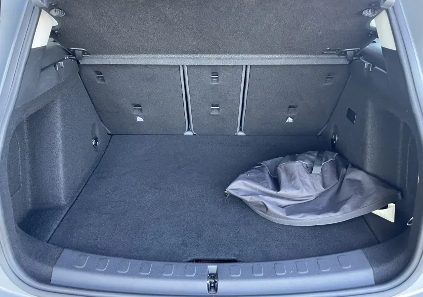 Coffre ouvert d'un MINI Countryman F60 hybride rechargeable gris Moonwalk, montrant un sac noir posé à droite.