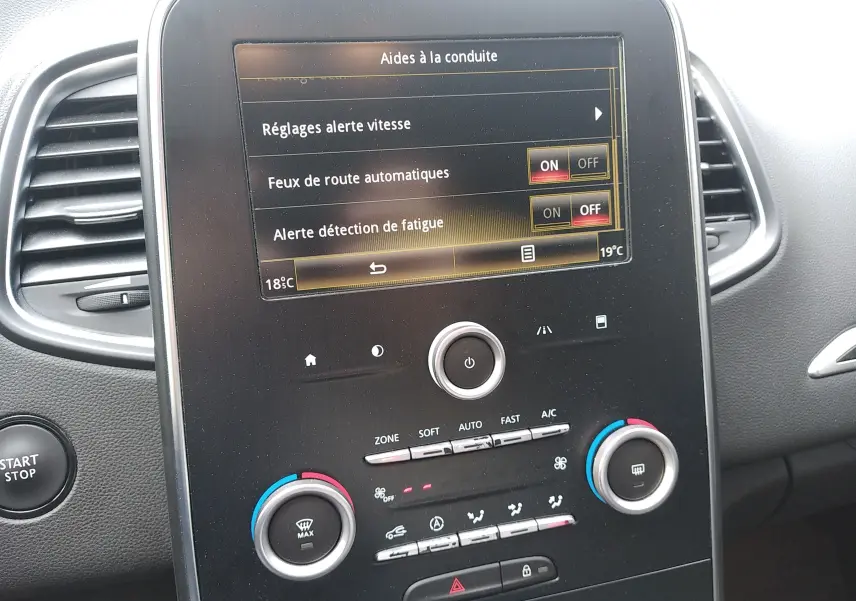 Écran tactile central du Renault Grand Scenic IV 2018 montrant les réglages d'aides à la conduite, avec commandes climatisation et bouton start/stop.