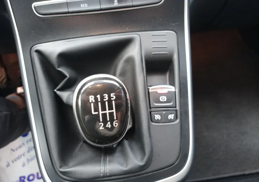 Gros plan sur le levier de vitesses manuel noir du Renault Grand Scenic IV avec commandes électroniques à droite.