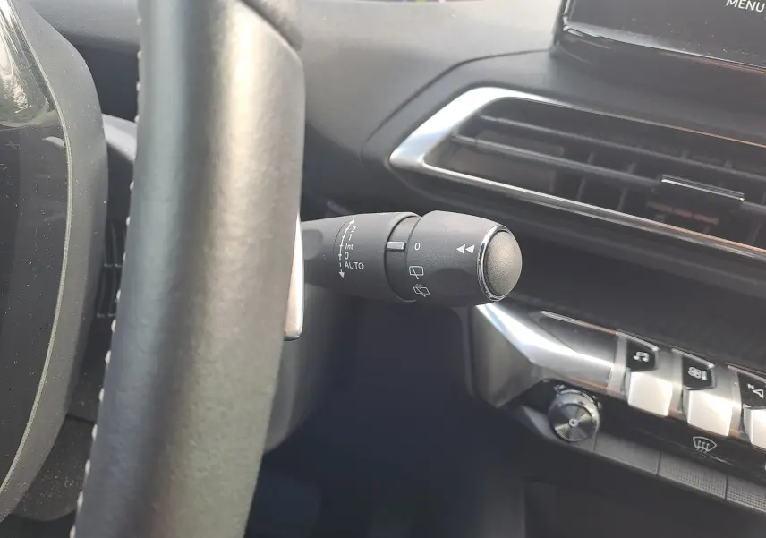 Gros plan sur la commande d'essuie-glace à gauche du volant dans l'habitacle gris du Peugeot 3008 Hybrid 2024.