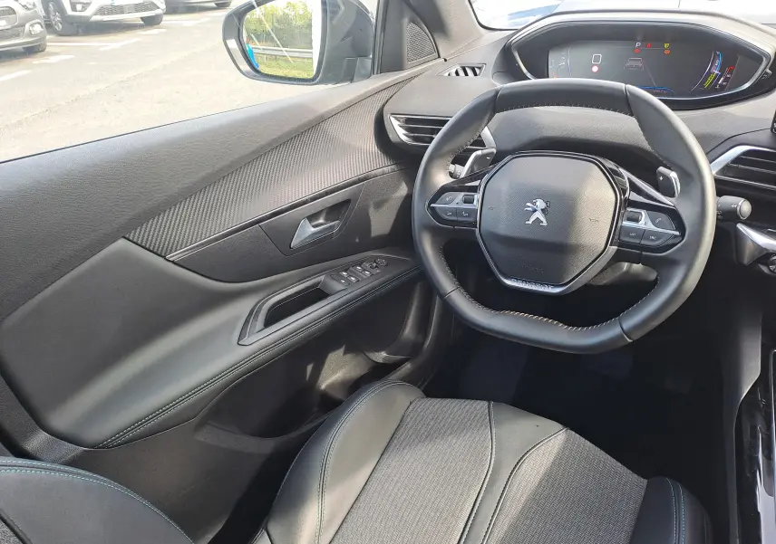 Vue intérieure côté conducteur du Peugeot 3008 Hybrid 145 Allure Pack 2024, volant compact et tableau de bord numérique.