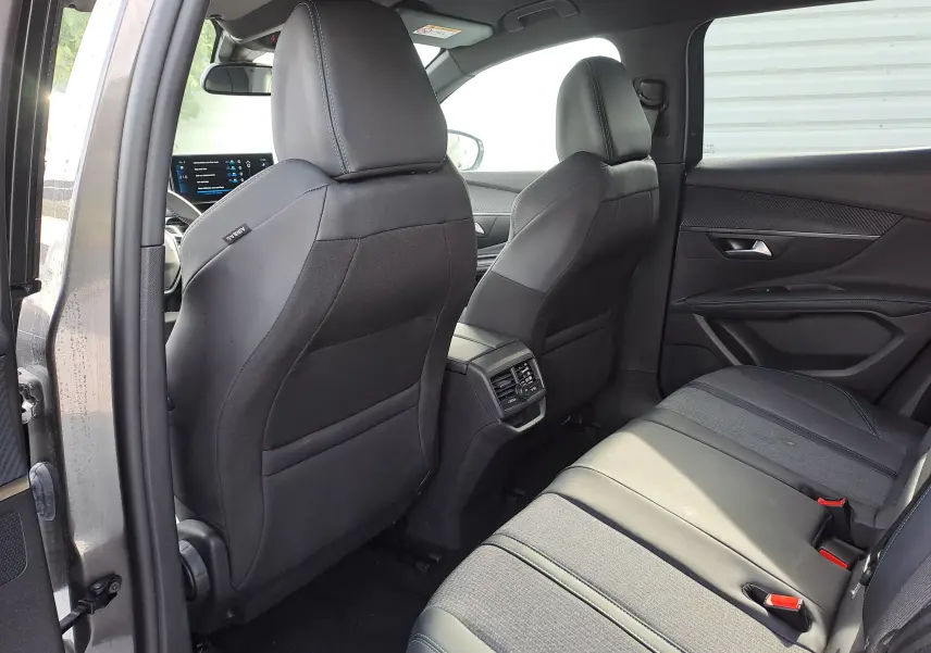 Vue intérieure arrière du Peugeot 3008 Hybrid gris platinium, montrant les sièges noirs et la console centrale avec aérateurs.