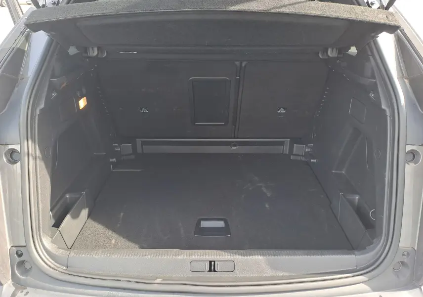 Coffre ouvert d'un Peugeot 3008 Hybrid gris platinium, montrant un espace de chargement propre et spacieux.
