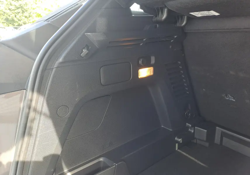 Détail de l'intérieur du coffre côté gauche du Peugeot 3008 gris platinium avec éclairage intérieur allumé.