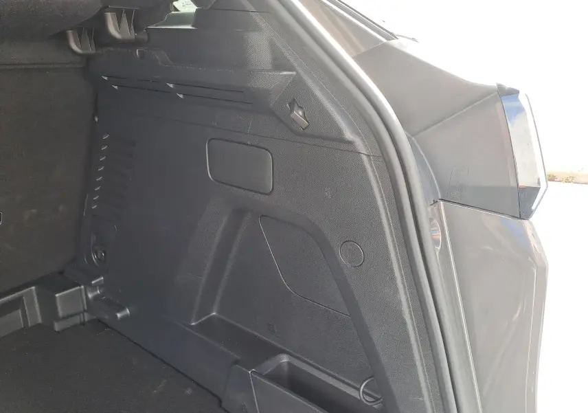 Vue rapprochée de l'intérieur du coffre côté droit d'un Peugeot 3008 Hybrid gris platinium 2024.